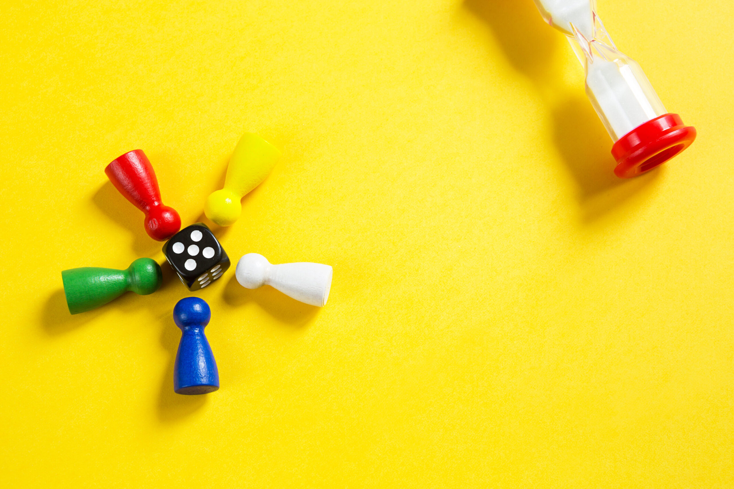Layout of board games on a yellow background: dice, chips, hourglass timer. Entertainment at home for children and adults. Copy space