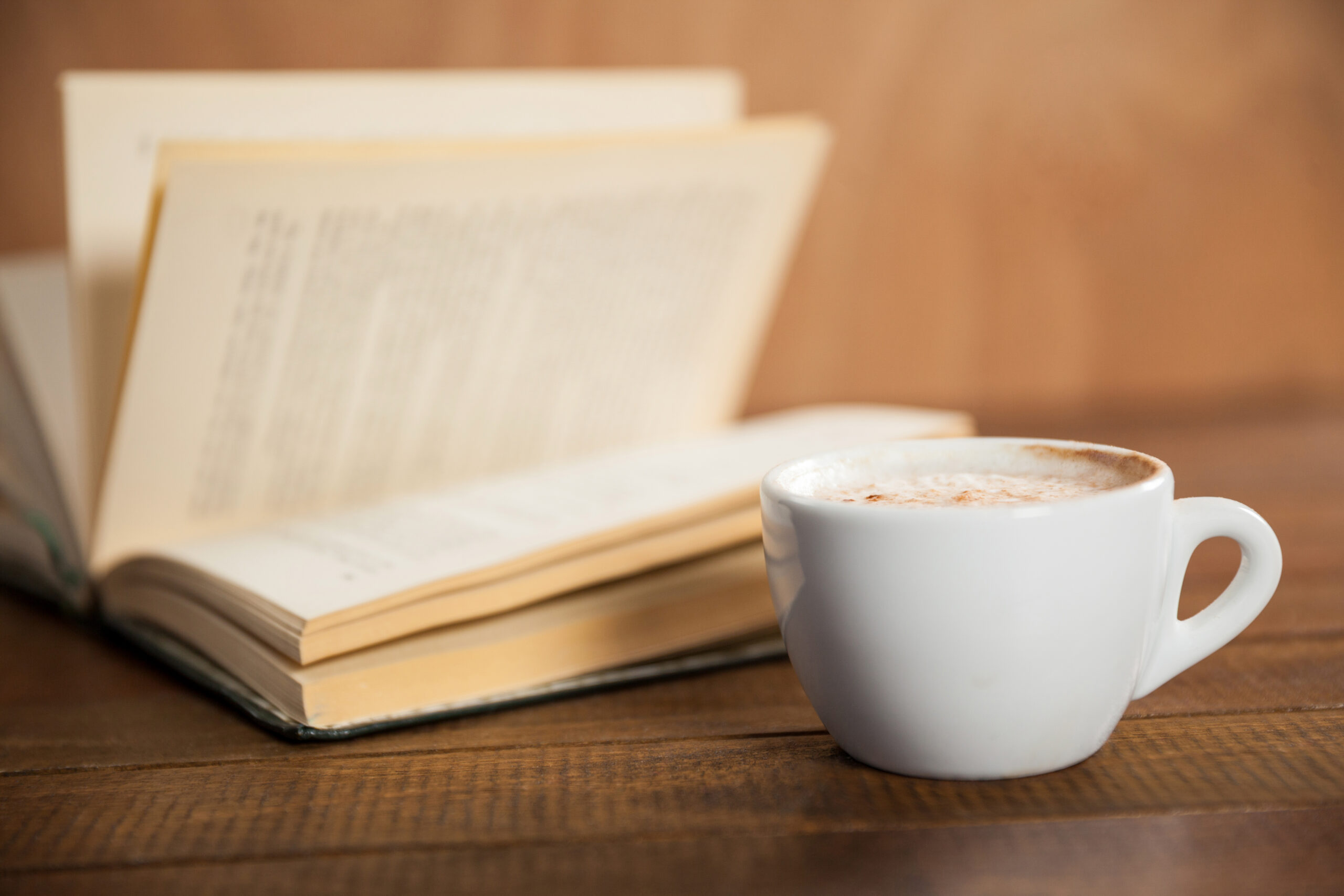 Close-up of coffee cup and book on wooden table